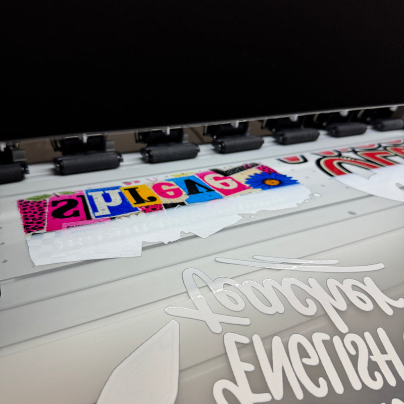 A gang sheet printing on a DTF printer, with the artwork printed mirrored on the film